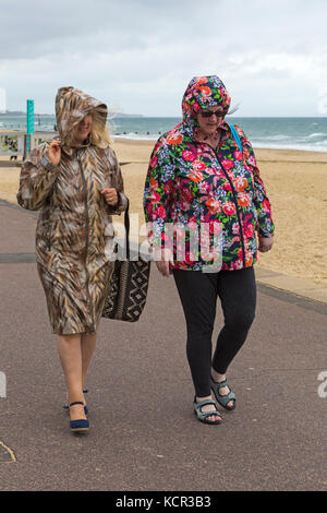 Bournemouth Dorset, Regno Unito. Il 7 ottobre, 2017. Regno Unito: meteo ariosi e coperto a Bournemouth Beach con qualche pioggerella, come due donne a piedi lungo la passeggiata lungomare di rivestimenti colorati con calotte fino. Credito: Carolyn Jenkins/Alamy Live News Foto Stock