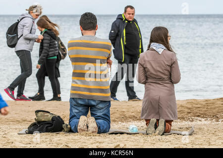 Danzica, Polonia. 7 ottobre 2017. I cattolici che si inginocchiano e pregano un rosario sulla riva del Mar Baltico si vedono a Danzica, in Polonia, il 7 ottobre 2017 i cattolici polacchi sono stati invitati a partecipare a una preghiera rosaria lungo il confine di countryÕs di 3.500 chilometri per pregare per "la loro patria e il mondo intero”. Il 7 ottobre è celebrato nella Chiesa cattolica romana come festa della Madonna del Rosario. Un totale di 319 chiese vicine ai confini polacchi sono state selezionate come punti di incontro per l'evento. Crediti: Michal Fludra/Alamy Live News Foto Stock