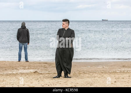 Danzica, Polonia. 7 ottobre 2017. Il sacerdote cattolico che prega un rosario sulla riva del Mar Baltico si trova a Danzica, in Polonia, il 7 ottobre 2017 i cattolici polacchi sono stati invitati a partecipare a una preghiera rosaria lungo il confine di countryÕs per 3.500 chilometri per pregare per "la loro patria e il mondo intero”. Il 7 ottobre è celebrato nella Chiesa cattolica romana come festa della Madonna del Rosario. Un totale di 319 chiese vicine ai confini polacchi sono state selezionate come punti di incontro per l'evento. Crediti: Michal Fludra/Alamy Live News Foto Stock