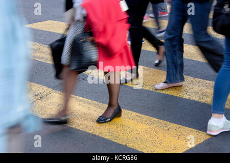 Sfocata gambe delle persone che camminano sulle strisce pedonali su una strada di città Foto Stock