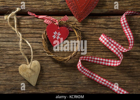 Vista aerea della forma di cuore decorazione con nastro e corona sul tavolo di legno Foto Stock