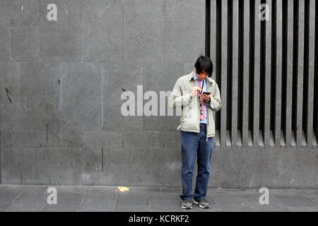 Uomo che utilizza il suo smart phone in una strada a King's Cross, Londra Foto Stock