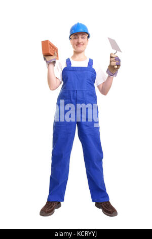 Costruzione femmina Lavoratore che indossa tuta blu e casco tenendo in acciaio inox cazzuola e mattone su sfondo bianco Foto Stock