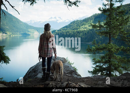 Vista posteriore della donna in piedi con il cane vicino al fiume Foto Stock