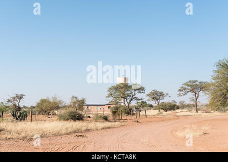 Una scena di strada con una casa ed un serbatoio di acqua in koes, una piccola città nella regione di karas in Namibia Foto Stock