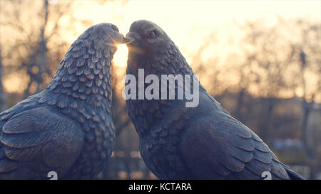 Coppia di vintage white pigeon in bronzo e sun sfondo. figurine piccioni in metallo. due figurine di piccioni come un monumento di amore. il monumento di amore in bronzo Foto Stock