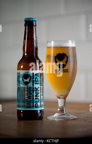 Una bottiglia di BrewDog Punk IPA si trova accanto al marchio BrewDog bicchiere riempito di birra (solo uso editoriale). Foto Stock