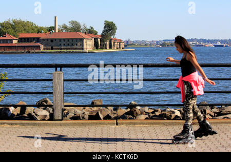 Una ragazza che rollerblading nel Liberty state Park con lo storico Ellis Island Immigrant Hospital in background.Jersey City.New Jersey.USA Foto Stock