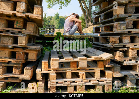 La donna a Monaco di Baviera, Settembre 24, 2017 Donna in crisi psicologica e depressione seduta su pallet in legno il 24 settembre 2017 a Monaco di Baviera, Germania. MOD Foto Stock