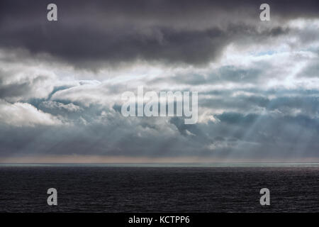 Nuvole temporalesche oltre il mare con raggi di sole che splende attraverso Foto Stock