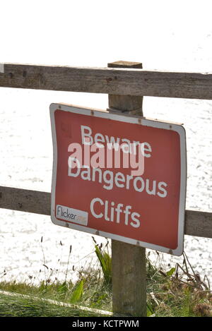 Un cartello di attenzione Dangerous Cliffs sul sentiero costiero, Filey, North Yorkshire UK Foto Stock