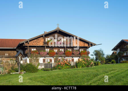 Case coloniche con facciata in legno nel tradizionale stile bavarese in Baviera con fiori che sbocciano nel sole del mattino, irschenberg, Baviera, Germania Foto Stock