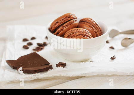 Pezzi di cioccolato sciolto con i chicchi di caffè e caffè aromatizzati macarons presentati su un tovagliolo bianco Foto Stock