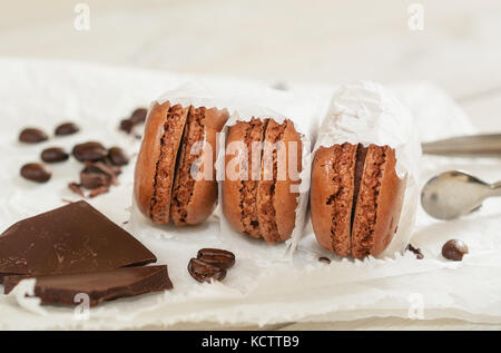 Pezzi di cioccolato sciolto con i chicchi di caffè e caffè aromatizzati macarons presentati su un tovagliolo bianco Foto Stock