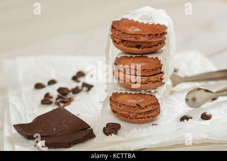 Pezzi di cioccolato sciolto con i chicchi di caffè e caffè aromatizzati macarons presentati su un tovagliolo bianco Foto Stock