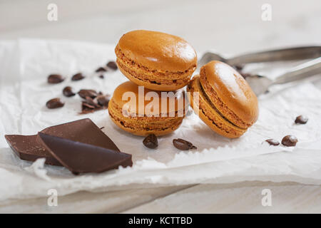 Pezzi di cioccolato sciolto con i chicchi di caffè e caffè aromatizzati macarons presentati su un tovagliolo bianco Foto Stock