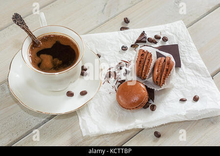 Pezzi di cioccolato con una tazza di caffè presentata su un tovagliolo bianco decorato con sciolto i chicchi di caffè e caffè aromatizzati macarons Foto Stock