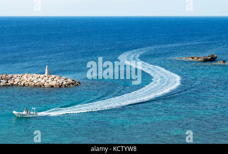 Un piccolo peschereccio abbandona una forma S wake come entra St Georges porto vicino aeroporto di Paphos a Cipro. Foto Stock