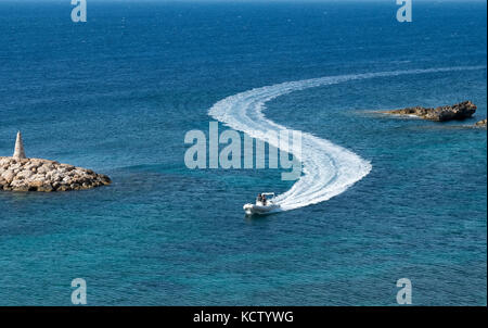 Un piccolo peschereccio abbandona una forma S wake come entra St Georges porto vicino aeroporto di Paphos a Cipro. Foto Stock