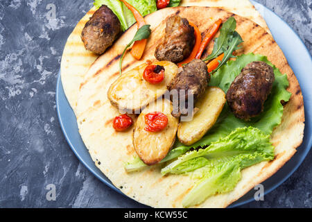 Tortilla piatto con salsicce di carne su pietra blu sullo sfondo Foto Stock