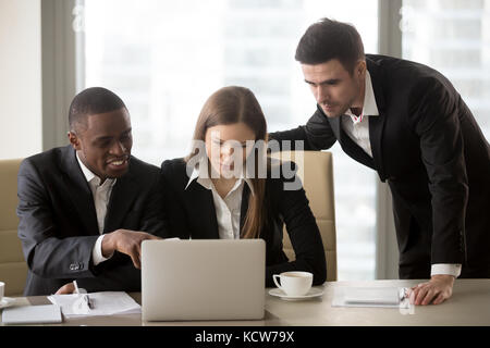 Gruppo di millenaria azienda multinazionale leader di discutere i dettagli del nuovo progetto mentre lavorando insieme su laptop in sala riunioni. giovani businessw Foto Stock