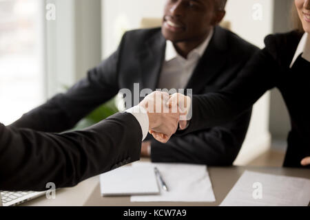 Immagine ravvicinata di una stretta di mano tra imprenditrice caucasica e cliente o partner in una riunione multinazionale in ufficio. Introduzione del candidato Foto Stock
