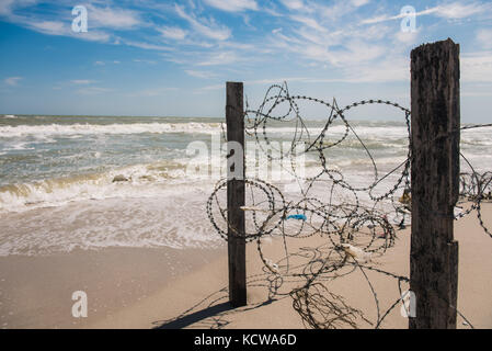 Il filo e il cielo blu con nuvole. lo spintore di sicurezza di filo spinato contro il blu del cielo e del mare Foto Stock