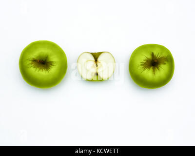 Mele Verdi top view fresche mele Granny Smith due mele intere e una metà di Apple sono giacenti orizzontalmente in una fila su un fondo bianco Foto Stock