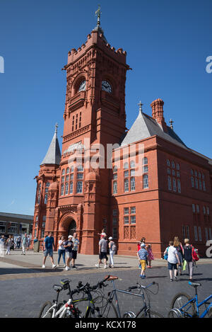 Edificio Pierhead (ex Bute Dock Company) con turisti e il parcheggio per le bici sulla zona pedonale, la Baia di Cardiff, Cardiff, Regno Unito Foto Stock