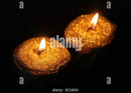 In prossimità dei due acceso candele oro su sfondo nero Foto Stock