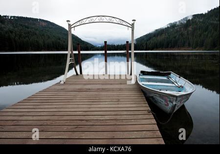 Un piccolo canotto è ancorata a un dock sul tranquillo lago specchio vicino sagle, Idaho. Foto Stock