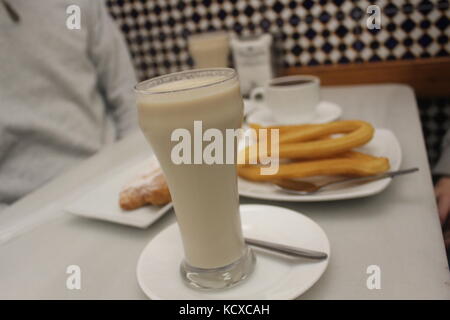 Un vetro freddo di horchata con churros, fartons e il cioccolato a un tradizionale horchateria a Valencia in Spagna. Foto Stock