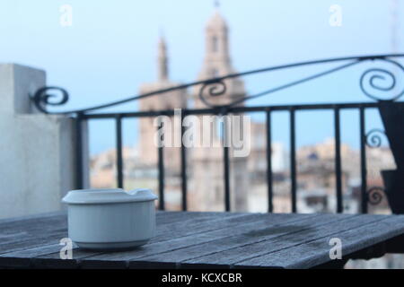 Posacenere bianco sul tavolo di legno a fuoco, con città sfocata in background. Foto Stock