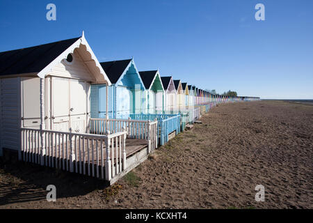 Cabine sulla spiaggia, contro un cielo blu a West Mersea, Essex, Inghilterra Foto Stock
