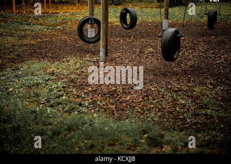 Parco giochi abbandonato pneumatico oscilla lonely giorno in autunno Foto Stock