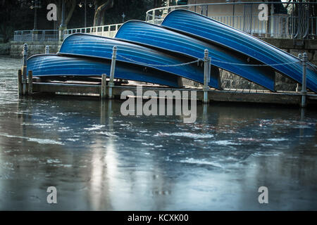 Quattro imbarcazioni a remi a un lago ghiacciato giacente sul molo Foto Stock