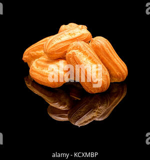 Grappolo di francese in casa Torte eclair senza smalto. Su un lucido nero lo sfondo con una vera riflessione. Foto Stock