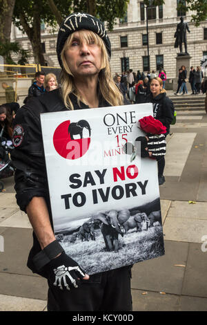 Londra, Regno Unito. Il 7 ottobre 2017. Una donna che tiene un poster con una fotografia di lelphants e il messaggio 'uno ogni quindici minuti - dire no all' Avorio alla protesta in piazza del Parlamento come un evento globale annuale di marzo per gli elefanti e rinoceronti (GMFER) svolge in tutto il mondo. Gli altoparlanti al termine di questa veglia ha invitato il governo britannico a introdurre un divieto completo su avorio e alla fine il commercio da parte di commercianti di antiquariato in Gran Bretagna che svolge un ruolo importante nel mantenere l'avorio mercati aperti e la guida del bracconaggio che minaccia di rendere gli elefanti e rinoceronti estinti. Peter Marshall / Alamy Live News. Foto Stock