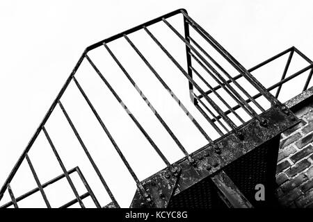 Bianco e nero immagine monocromatica di una formazione di ruggine ferro incorniciato fire escape che mostra l'invecchiamento in un paesaggio urbano Foto Stock