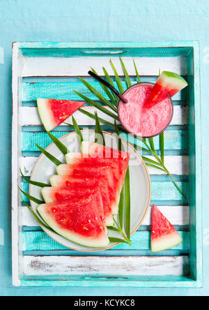 Frullato di anguria, succo di frutta fresco su legno colorato sfondo con foglie di palma. Vista dall'alto. Copia dello spazio. Foto Stock