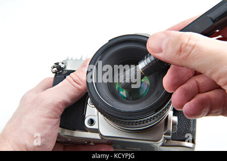 Pulizia della lente fotografica dalla polvere con una spazzola Foto Stock