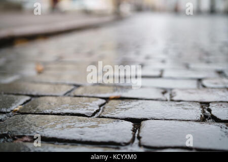 Bassa angolazione del wet vecchio marciapiede in Tallinn con messa a fuoco poco profonda Foto Stock