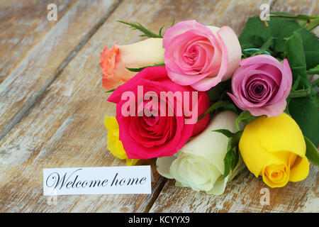 Benvenuti home card con colorate bouquet di rose sul rustico superficie in legno Foto Stock