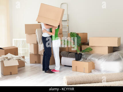 Giovane baciare con box su capi nella loro nuova casa Foto Stock