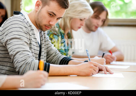 Studente universitario cercando di copiare un test di Student carta. Foto Stock