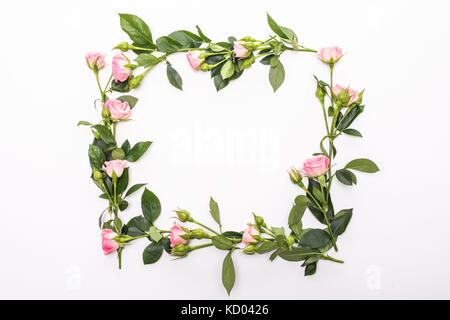 Cornice rotonda con rosa boccioli di fiori, rami e foglie isolati su sfondo bianco. piatta, vista dall'alto Foto Stock