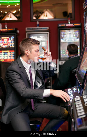 Uomo bello essere concentrato nel giocare alle slot machine Foto Stock