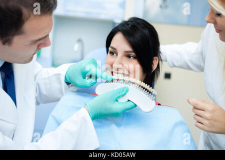 Dentista confrontando i denti del paziente in ombra con i campioni per il trattamento di sbianca Foto Stock