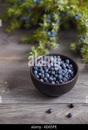 Piccola ciotola con semi di ginepro su tavolo di legno. Foto Stock