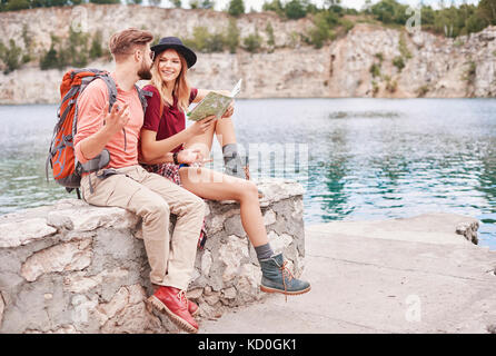 Giovane seduto sulla parete da acqua guardando la mappa, Cracovia, malopolskie, Polonia, europa Foto Stock